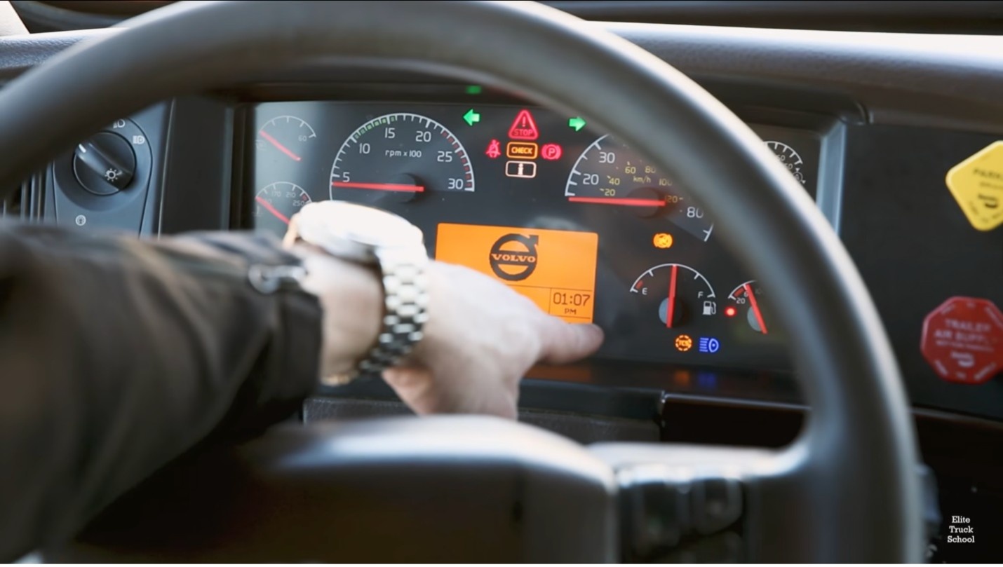 Truck driver operating a semi-truck dashboard and instrument panel during CDL training