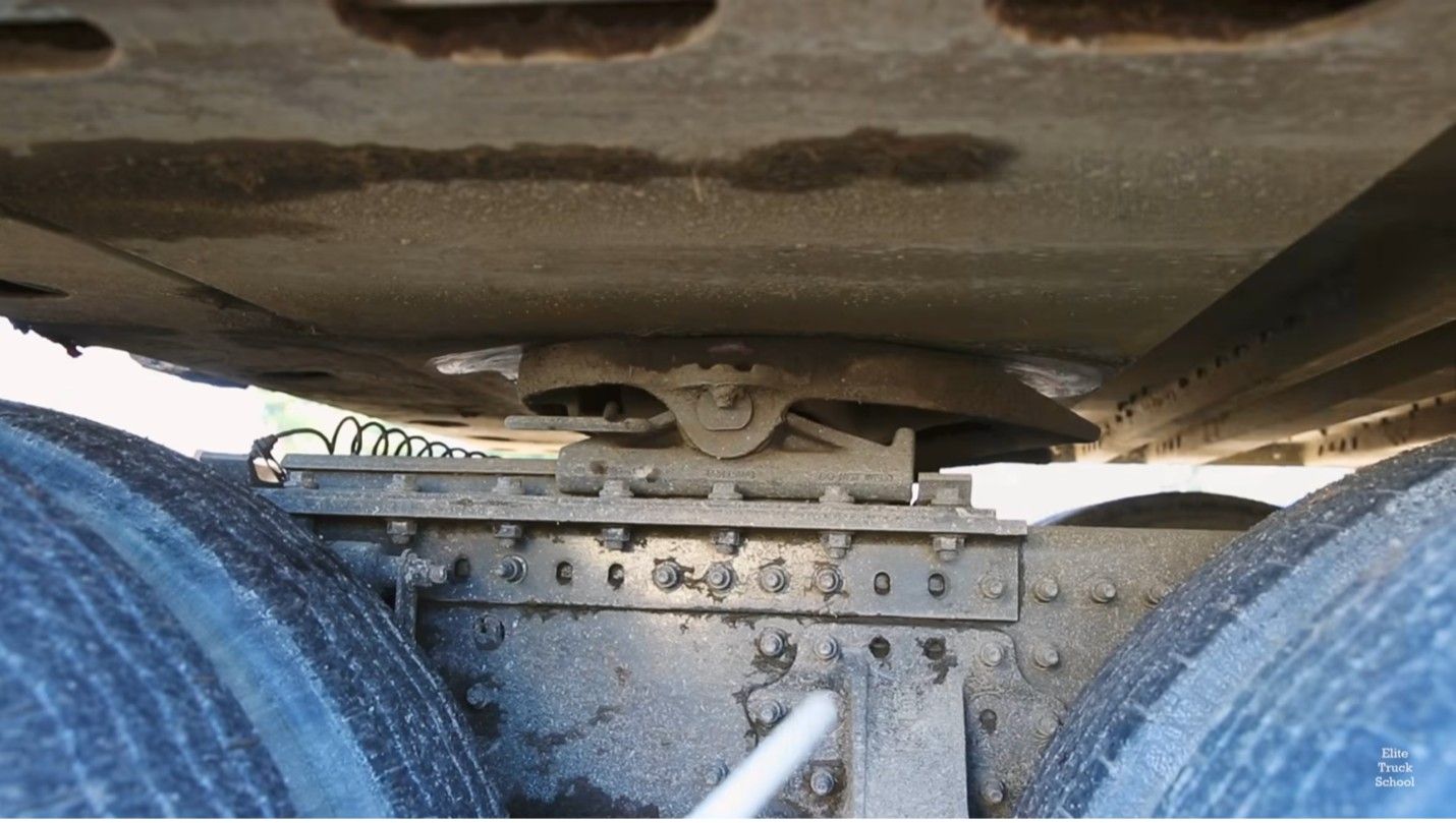 Close-up of a semi-truck fifth wheel coupling during a CDL pre-trip inspection