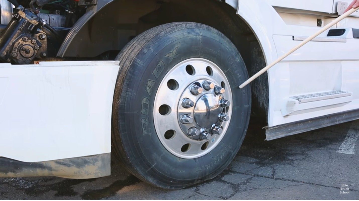 Close-up of a semi-truck fifth wheel coupling during a CDL pre-trip inspection