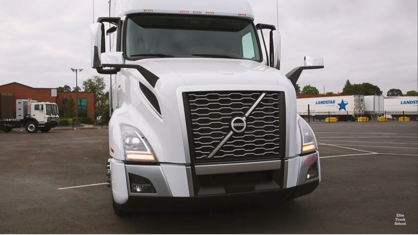 Front view of a semi-truck with headlights on during a CDL pre-trip lighting inspection at a truck driving school