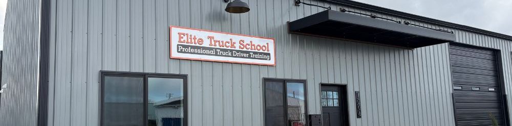 Image of Elite Truck School's Albany Campus building with a white and orange "Elite Truck School" sign above the font doors.