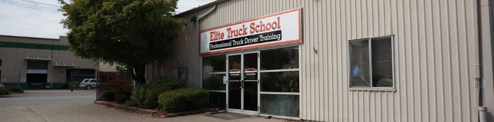 Image of Elite Truck School's Portland Campus building with a tree to the left and a white and orange "Elite Truck School" sign above the front doors.