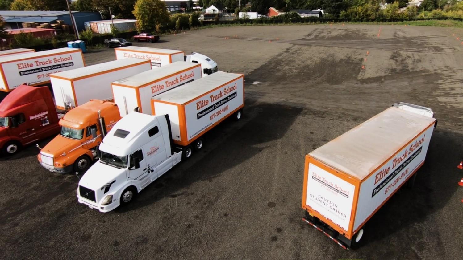 Drone shot of four Elite semi trucks parked in dirt training lot