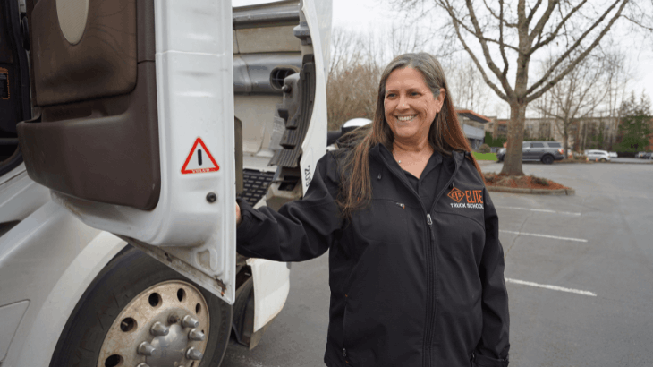 Nicole smiling and standing next to semi truck cab