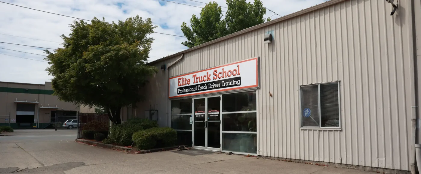 Exterior of the Portland location, a tan metal building with a signed glass-door entrance, a tree out front, and neighboring warehouses.