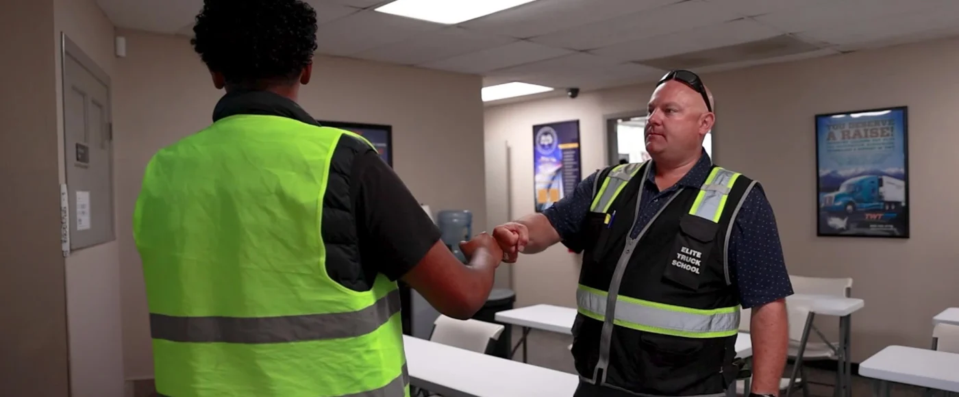 Instructor and student fist bumping in classroom
