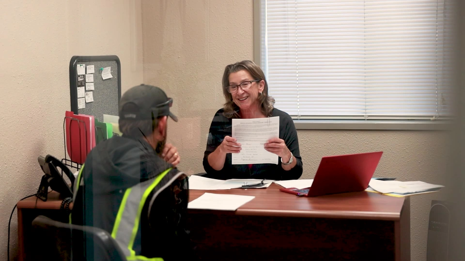 A smiling admissions representative holds up a completed form while meeting with a student